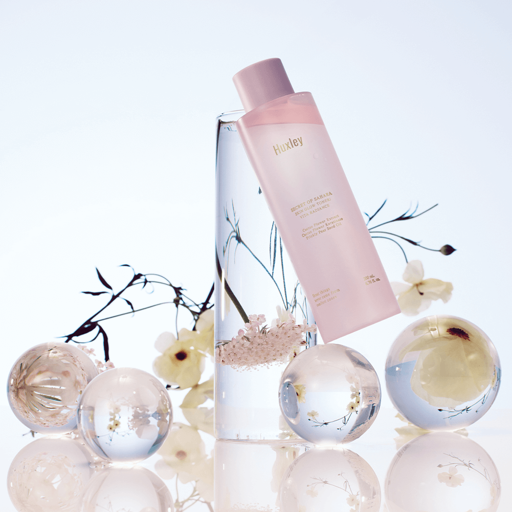 HUXLEY Skin Glow Toner Vita Radiance with decorative floral elements and glass spheres, enhancing beauty and radiance.
