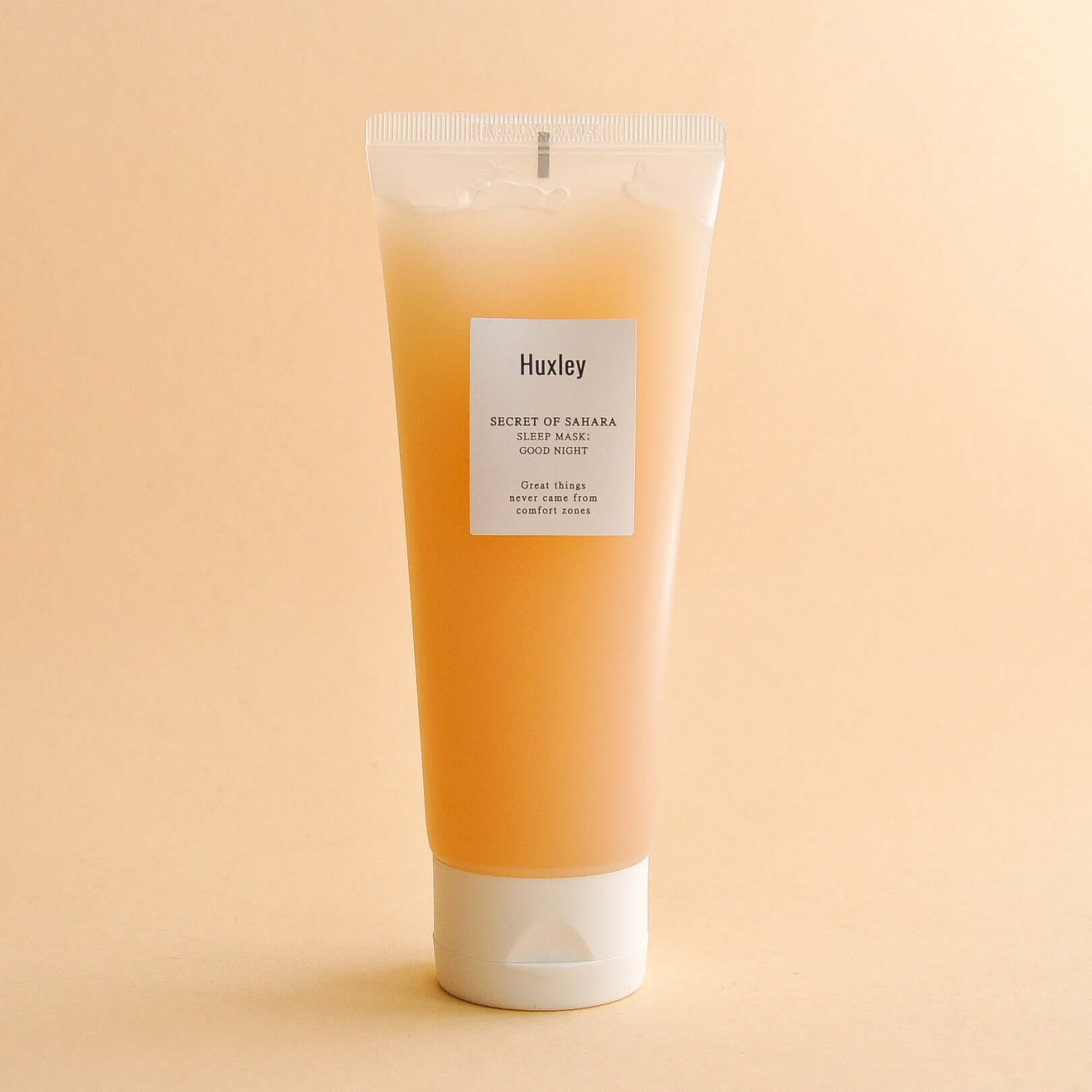 HUXLEY Sleep Mask Good Night tube on a beige background, showcasing the skincare product's packaging and label.
