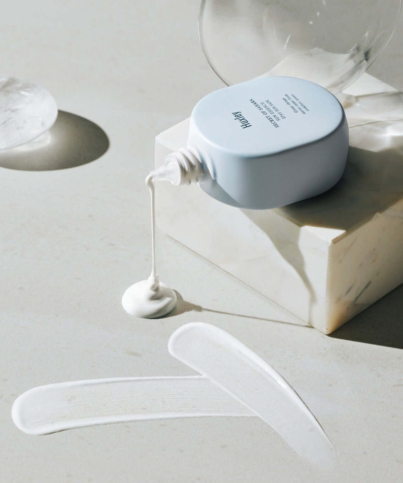 HUXLEY Sun Essence Stay Sun Safe sunscreen pouring on marble surface