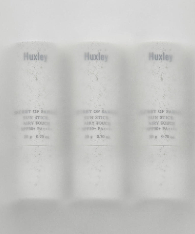 Image of HUXLEY Sun Stick Airy Touch 20g, featuring three sleek white containers in a row, emphasizing sun protection and skincare convenience.