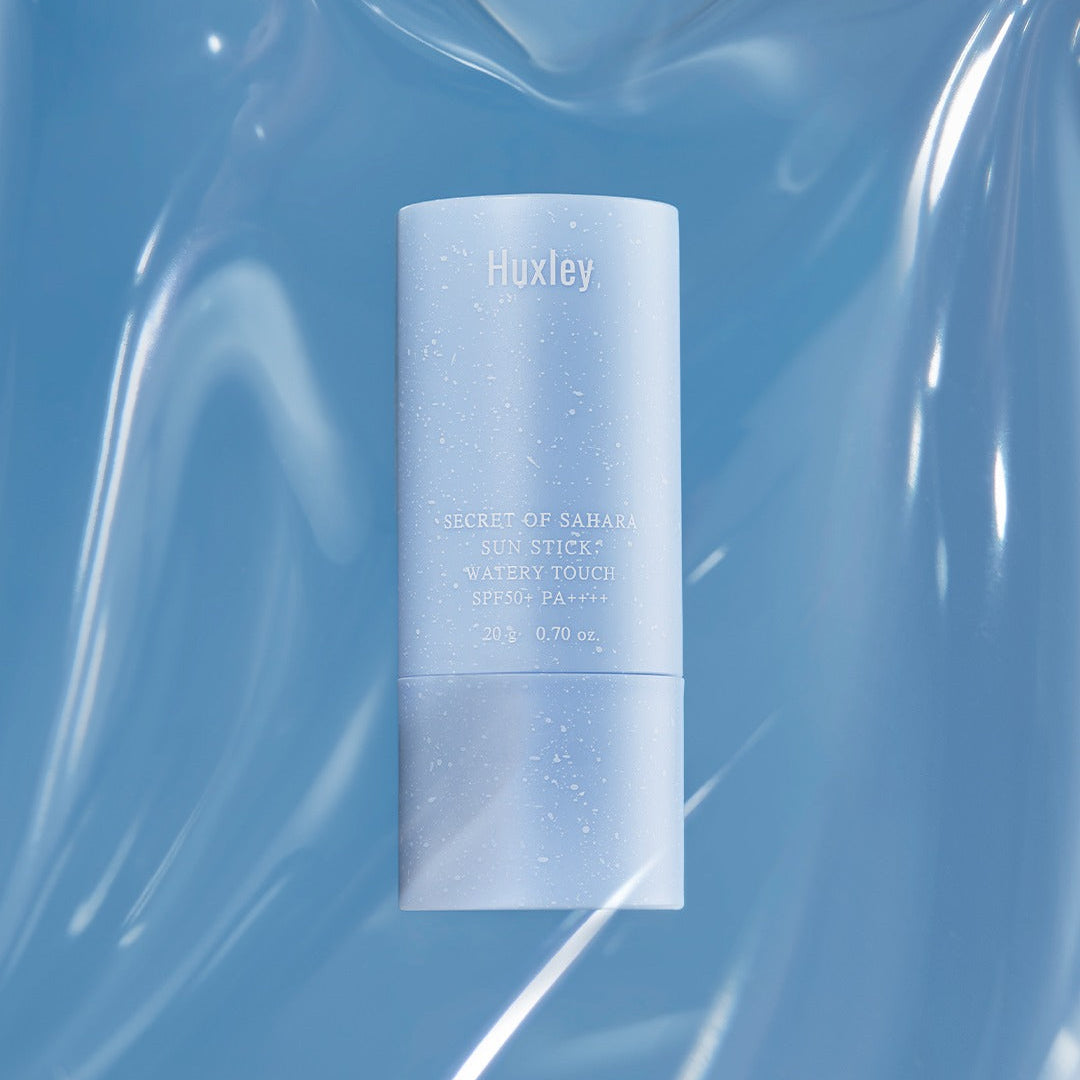 HUXLEY Sun Stick Watery Touch 20g displayed on a reflective surface, showcasing its sleek design and SPF protection.
