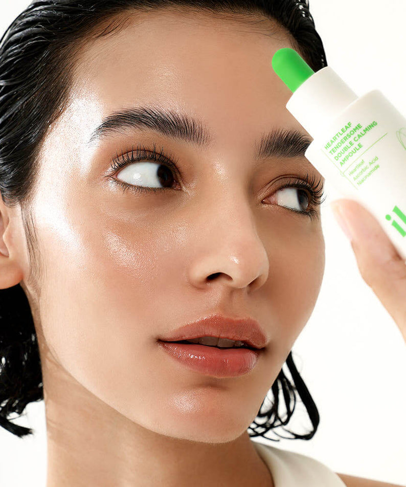 Woman using ILSO Eoseongcho Tenderjom Double Calming Ampoule 30ml for skincare routine, close-up.