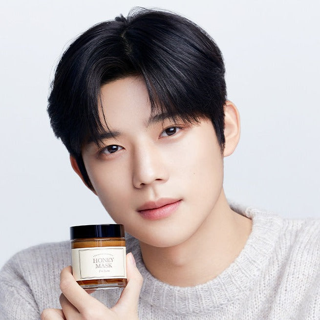 Person holding I'M FROM Honey Mask 120g jar, showcasing skincare product in a clear container with a cheerful expression.