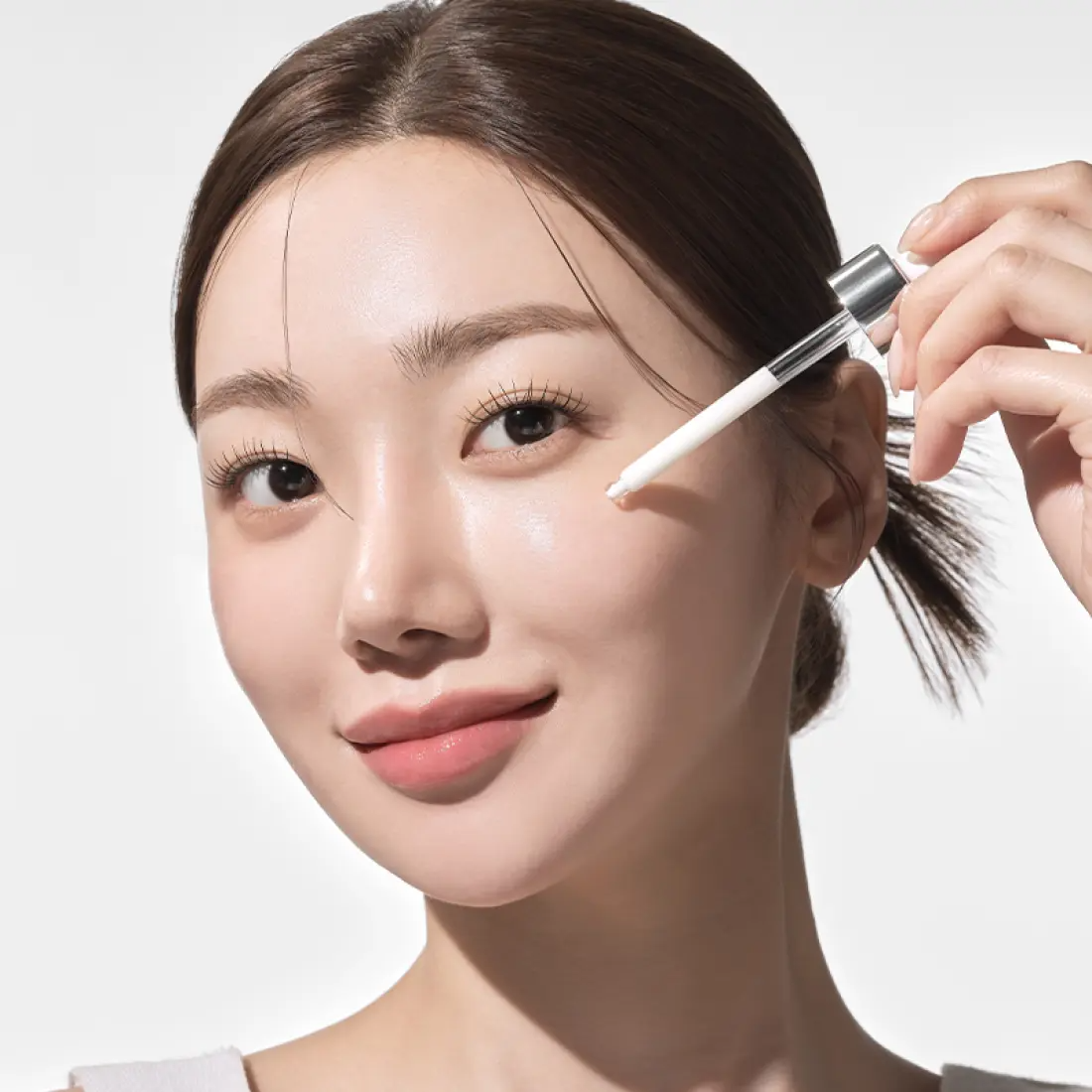 Woman applying IOPE UV Sheild Sun Ampoule SPF 50+PA+++ 40ml to her cheek for sun protection and skincare