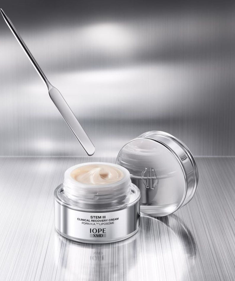 IOPE XMD Stem3 Clinical Recovery Cream 50ml with spatula on metallic background