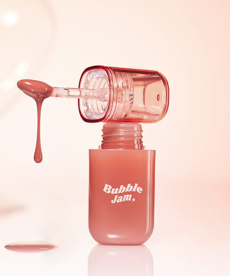 IPKN Bubble Jam Gloss with applicator dripping gloss, showcasing texture and color in a clear bottle against a soft background.