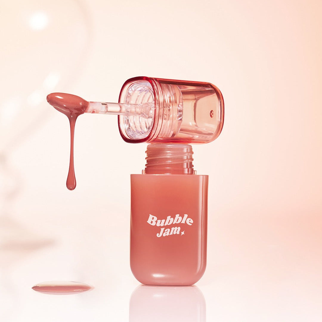 IPKN Bubble Jam Gloss with applicator dripping gloss, showcasing texture and color in a clear bottle against a soft background.