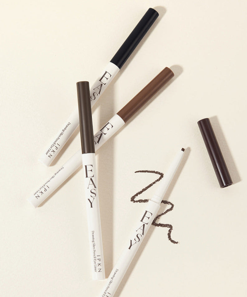 Assorted shades of IPKN Easy Drawing Slim Pencil Eyeliner on a beige background.