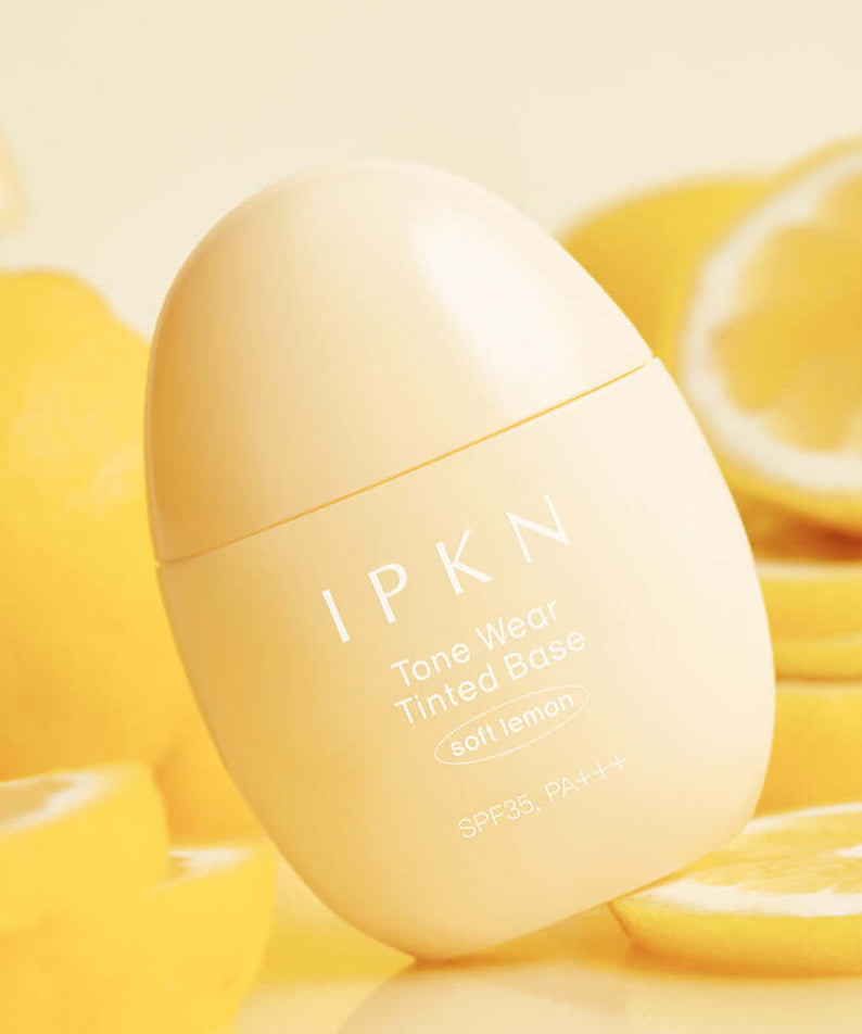 IPKN Tone Wear Tinted Base in soft lemon shade, surrounded by fresh lemons, SPF35 PA+++