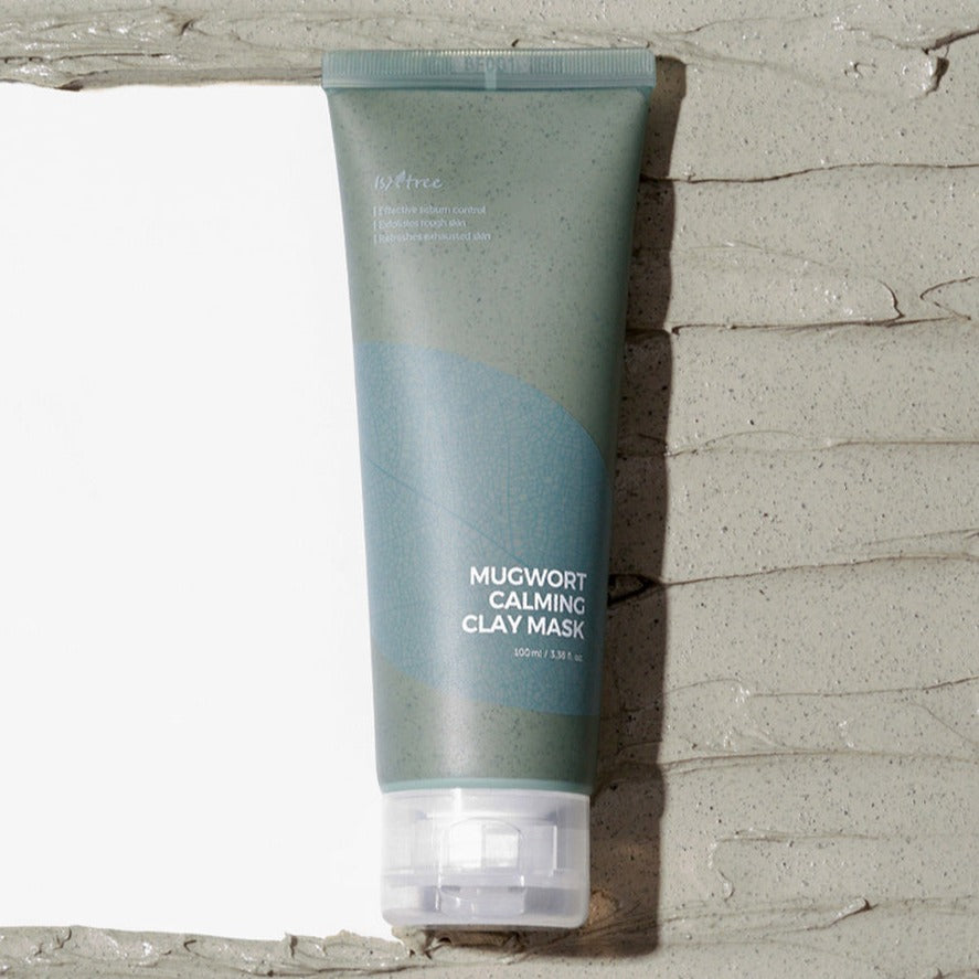 ISNTREE Mugwort Calming Clay Mask 100ml tube on clay background showing packaging details.