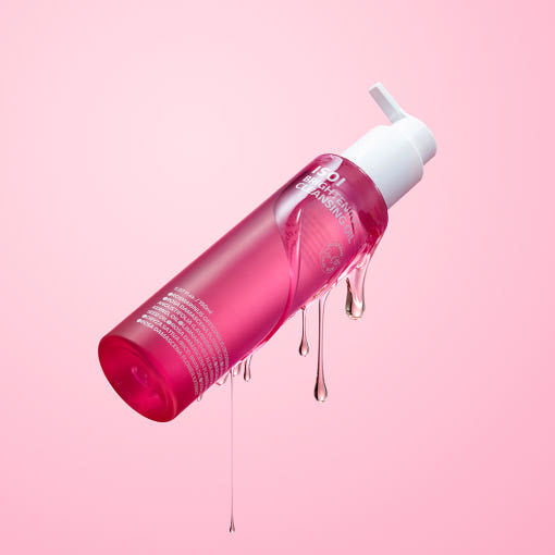 ISOI Brightening Cleansing Oil 150ml bottle with oil dripping on pink background.