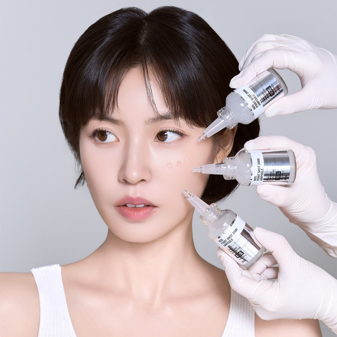 Person applying ISOI NDS Point Shot 2000 Ampoule 38ml on skin for skincare treatment.