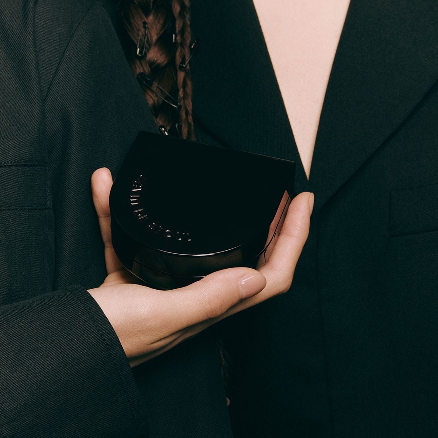 Person holding JAVIN DE SEOUL Wink Cushion Glow 16g compact in hand, showcasing sleek design.
