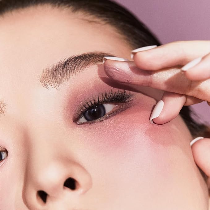 Model applying JAVIN DE SEOUL Wink Eye Shade Primer to eyelid, showcasing makeup application.