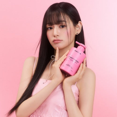 Woman holding JULYME Damage Care Perfume Hair Shampoo 500ml bottle with pink background.