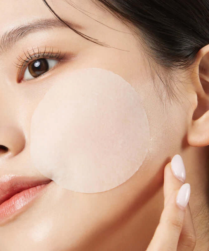 Woman using JUMISO Antioxidant Glow Toning Pads 70 Sheets on cheek for skincare routine