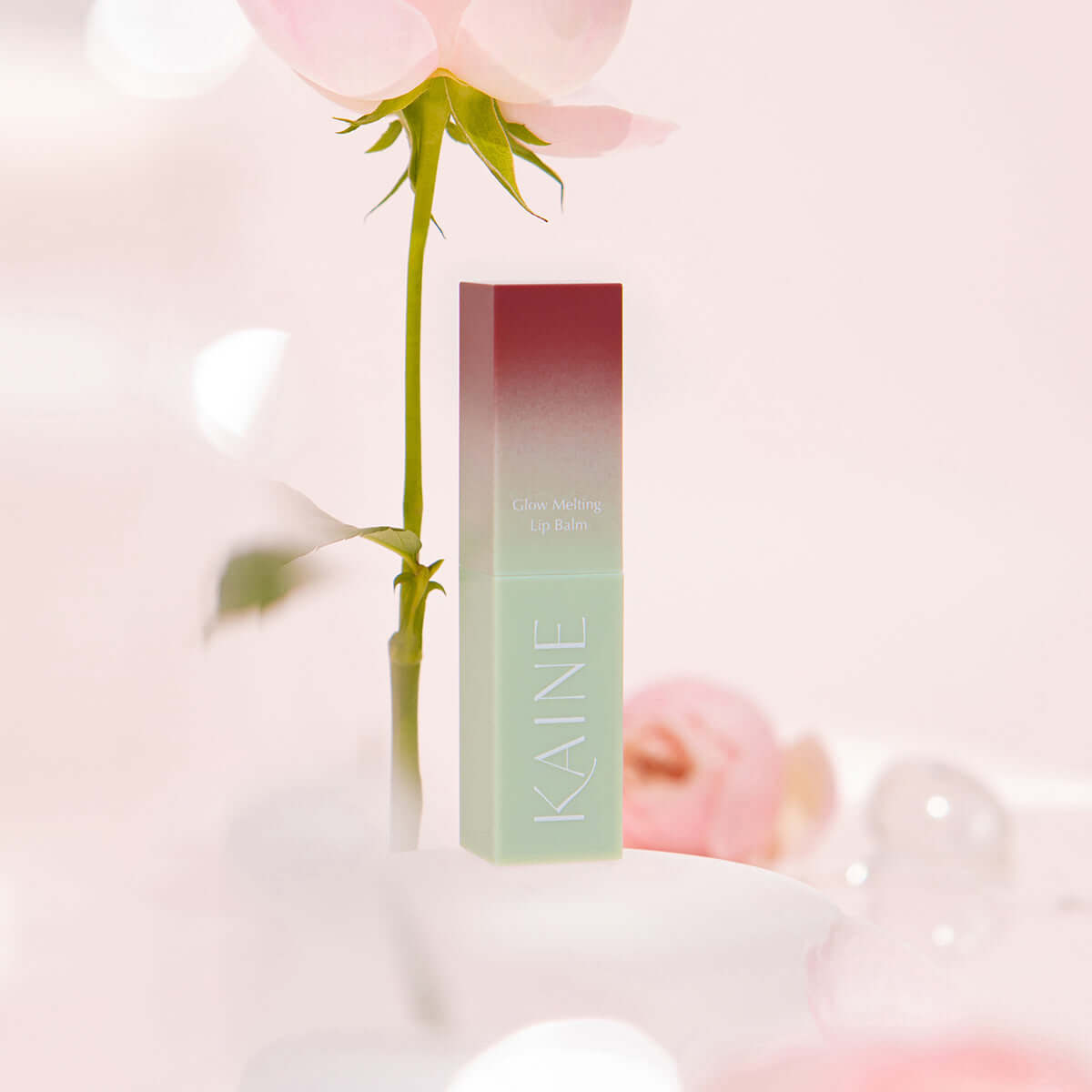 KAINE Glow Melting Lip Balm with elegant packaging and soft pink background