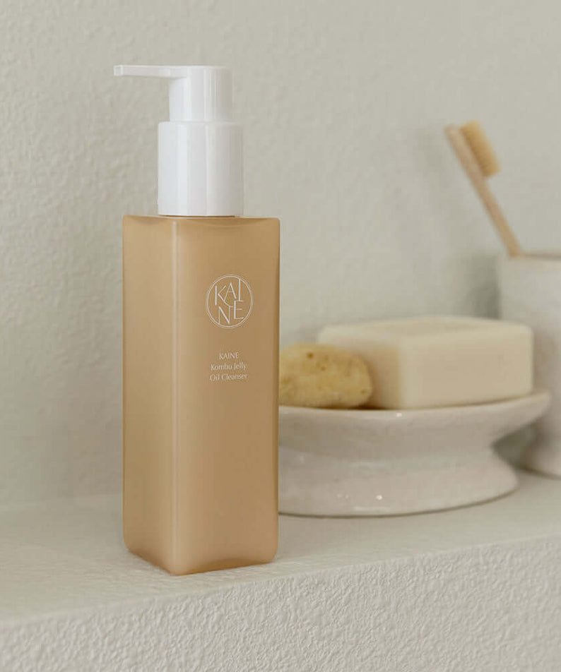 KAINE Kombu Jelly Oil Cleanser 145ml bottle on bathroom shelf surrounded by soap and sponge