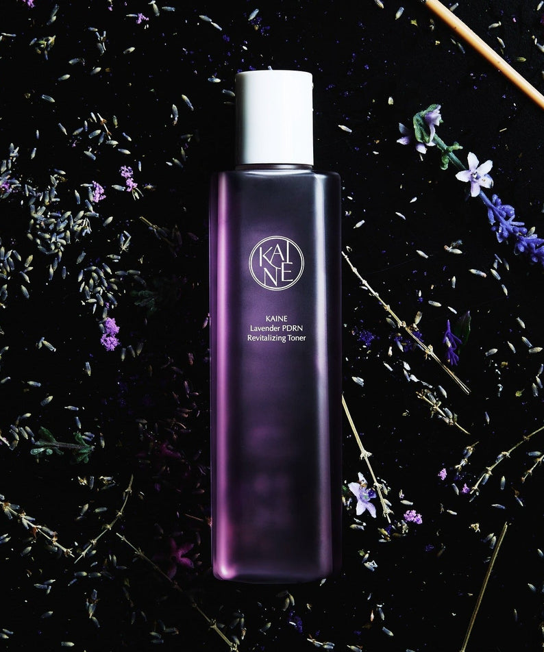 KAINE Lavender PDRN Revitalizing Toner 300ml bottle surrounded by lavender flowers on a dark background.