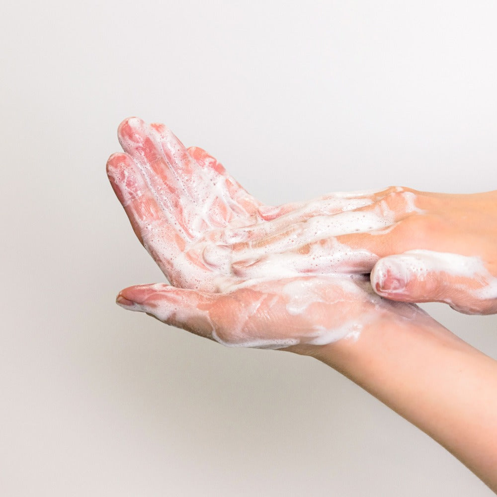 Hands lathered with foam using KAINE Rosemary Acne Mildly Acidic Cleansing Bar 100g, showing cleansing effectiveness.