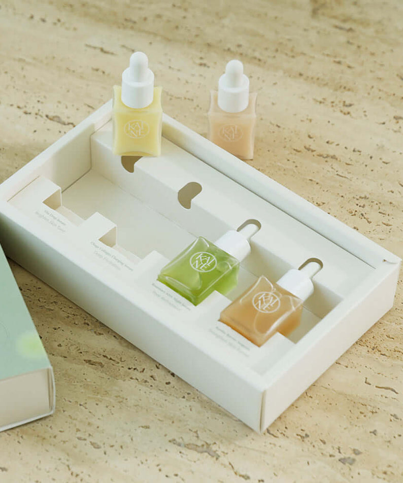KAINE Serum Discovery Kit with three different serum bottles in an elegant packaging, set on a textured background.