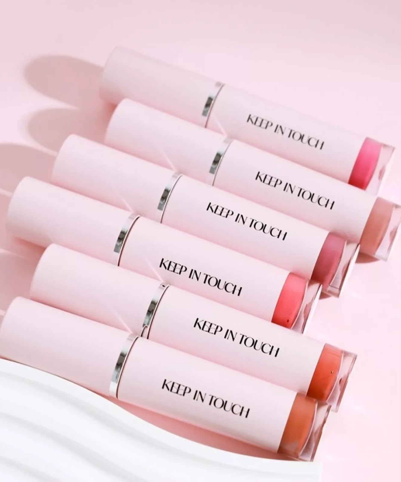 Six shades of KEEP IN TOUCH Glow Water Lip Tint arranged on a pink background.