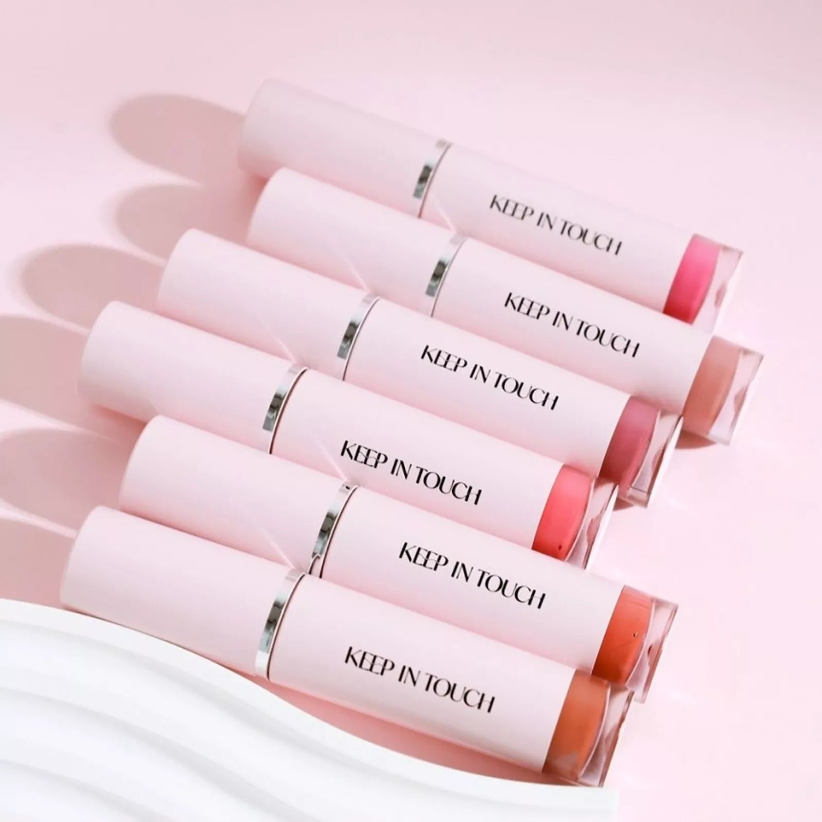 Six shades of KEEP IN TOUCH Glow Water Lip Tint arranged on a pink background.