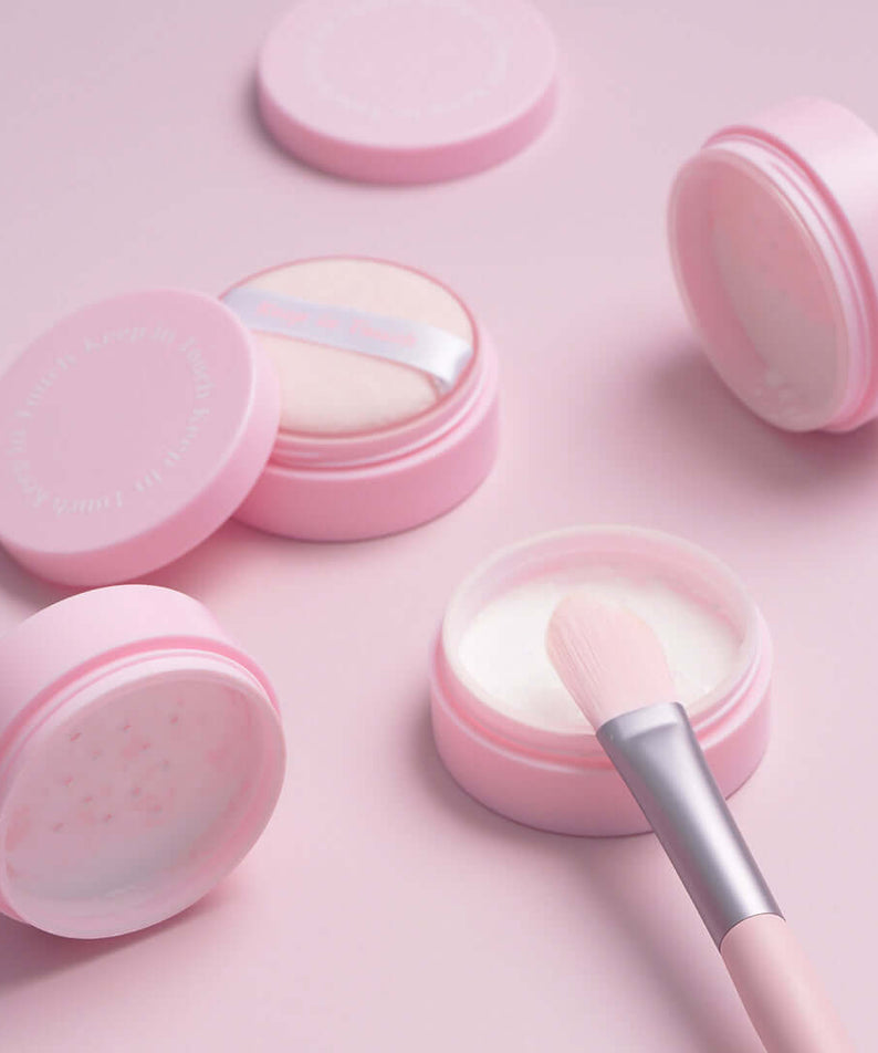 KEEP IN TOUCH Mini Pore Eraser Powder in pink containers with applicator brush, perfect for minimizing pores and evening skin tone.