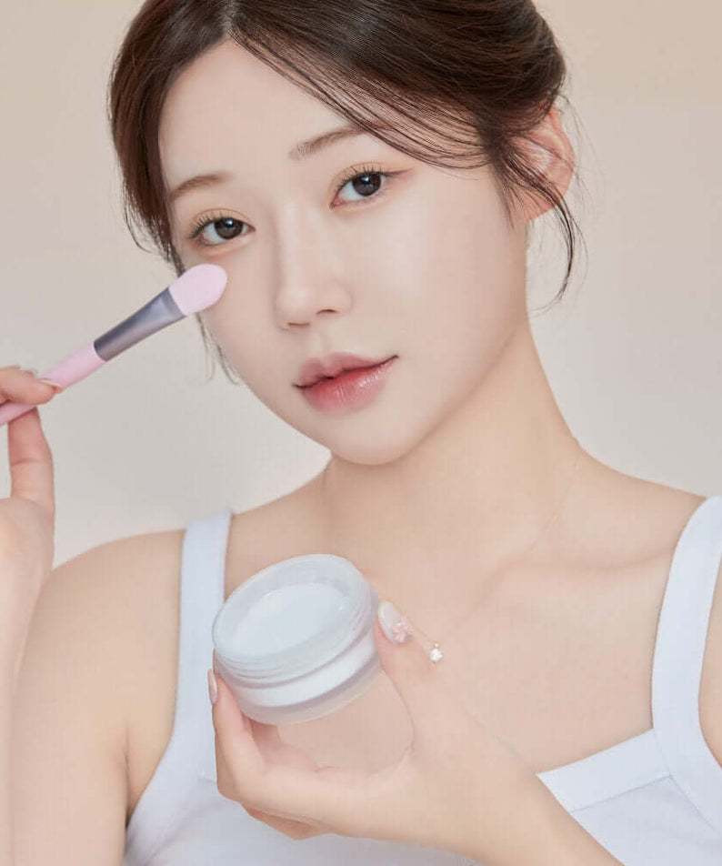 Woman applying KEEP IN TOUCH Mini Pore Eraser Powder with a brush for smooth skin