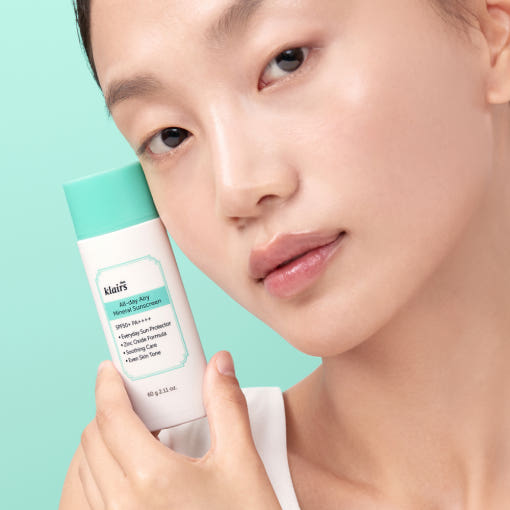 KLAIRS All Day Airy Invisible Tone-Up Sunscreen 60g (SPF50+ PA++++), woman holding the sunscreen next to her face, showcasing product.