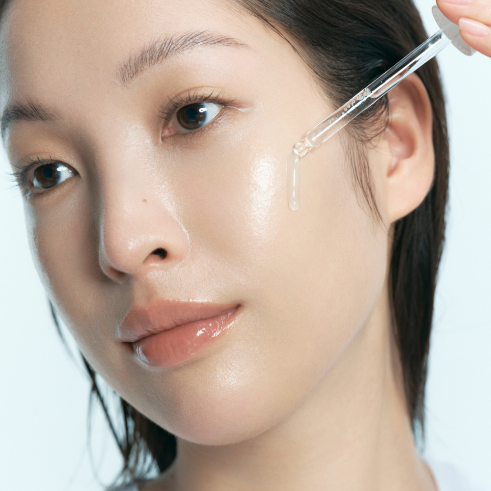 Model applying KLAIRS EGF Blue AC Soothing Serum 50g on face with dropper for glowing skin.