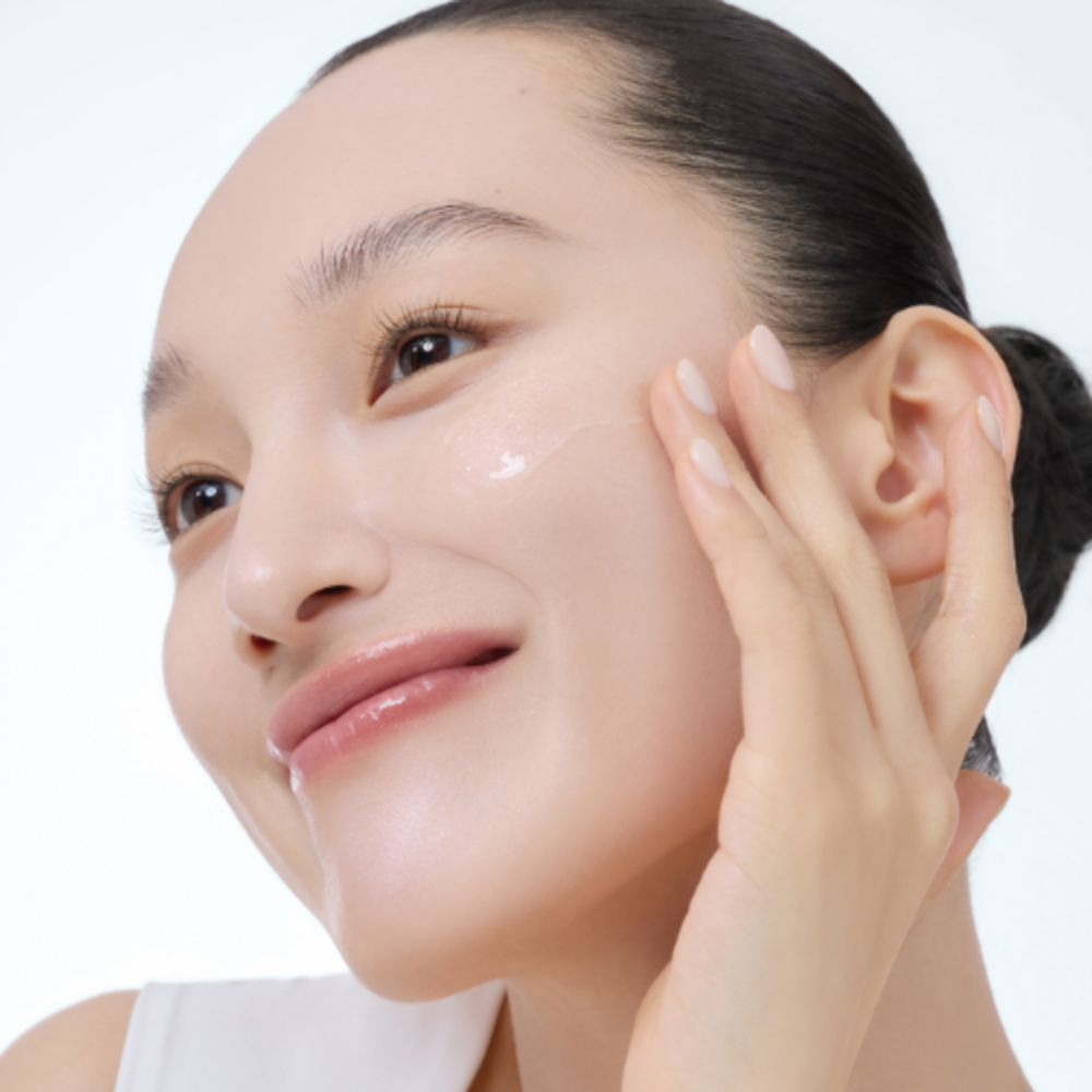 Woman applying skincare, smiling, healthy skin, moisturizing, beauty routine.