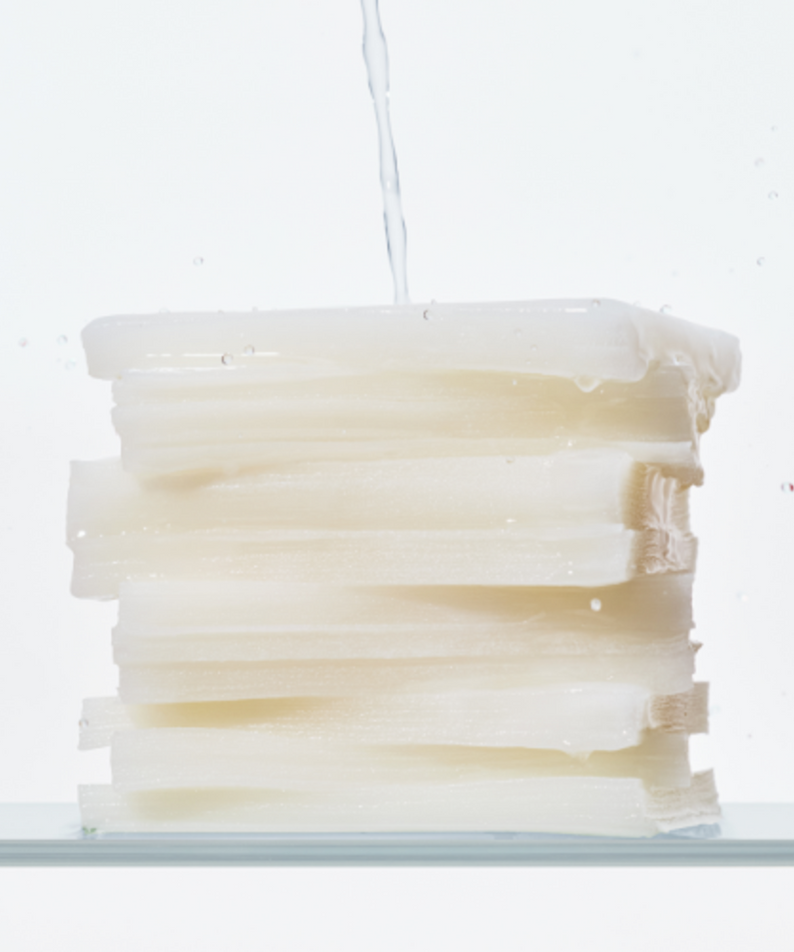 Stack of KLAIRS Freshly Juiced Vitamin Hwajalmeok Pad 80 sheets with water droplets on top, illustrating hydration and freshness.