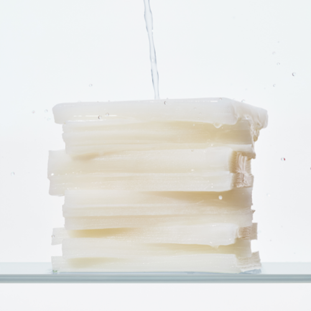 Stack of KLAIRS Freshly Juiced Vitamin Hwajalmeok Pad 80 sheets with water droplets on top, illustrating hydration and freshness.