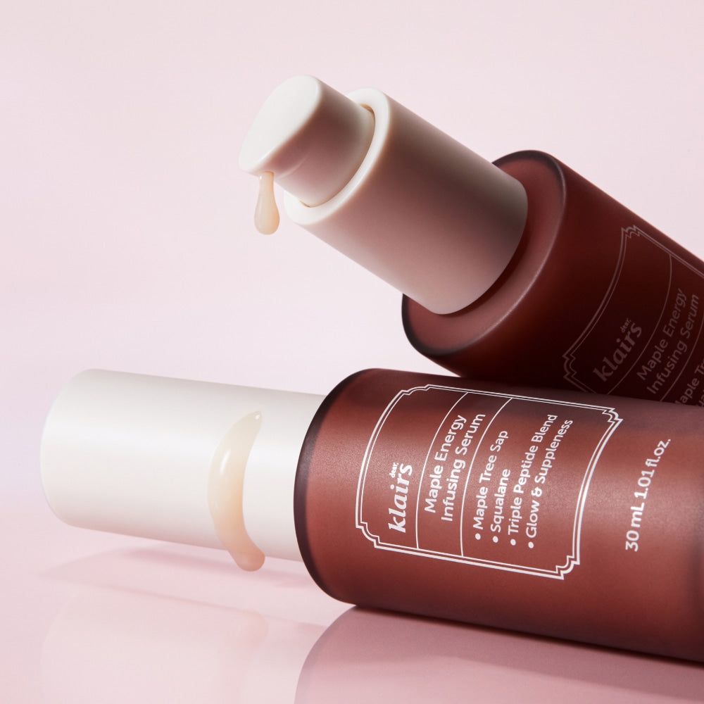 Two bottles of KLAIRS Maple Energy Infusing Serum 30ml with droppers, showcased against a pink background.