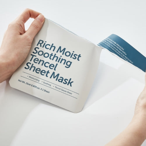 Hands holding KLAIRS Rich Moist Soothing Tencel Sheet Mask packaging.