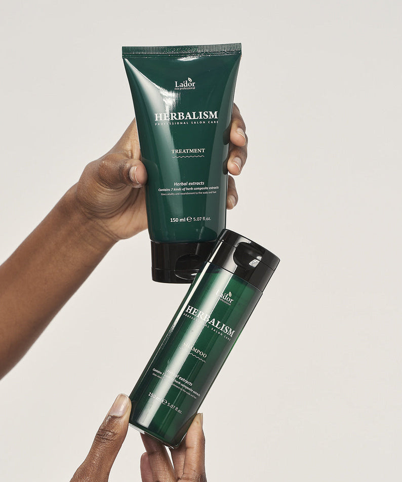 Two bottles of LADOR Herbalism Treatment 150ml being held.