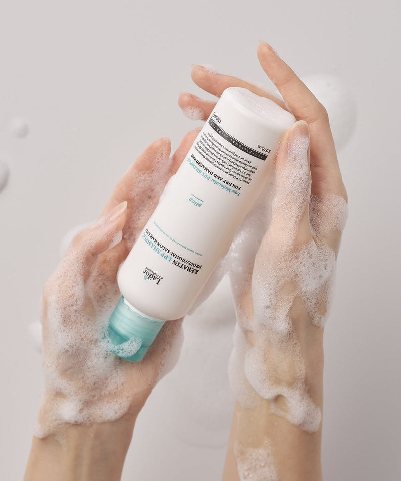 Hands holding LADOR Keratin LPP Protein Shampoo 150ml with foamy lather, showcasing the nourishing formula for hair care.