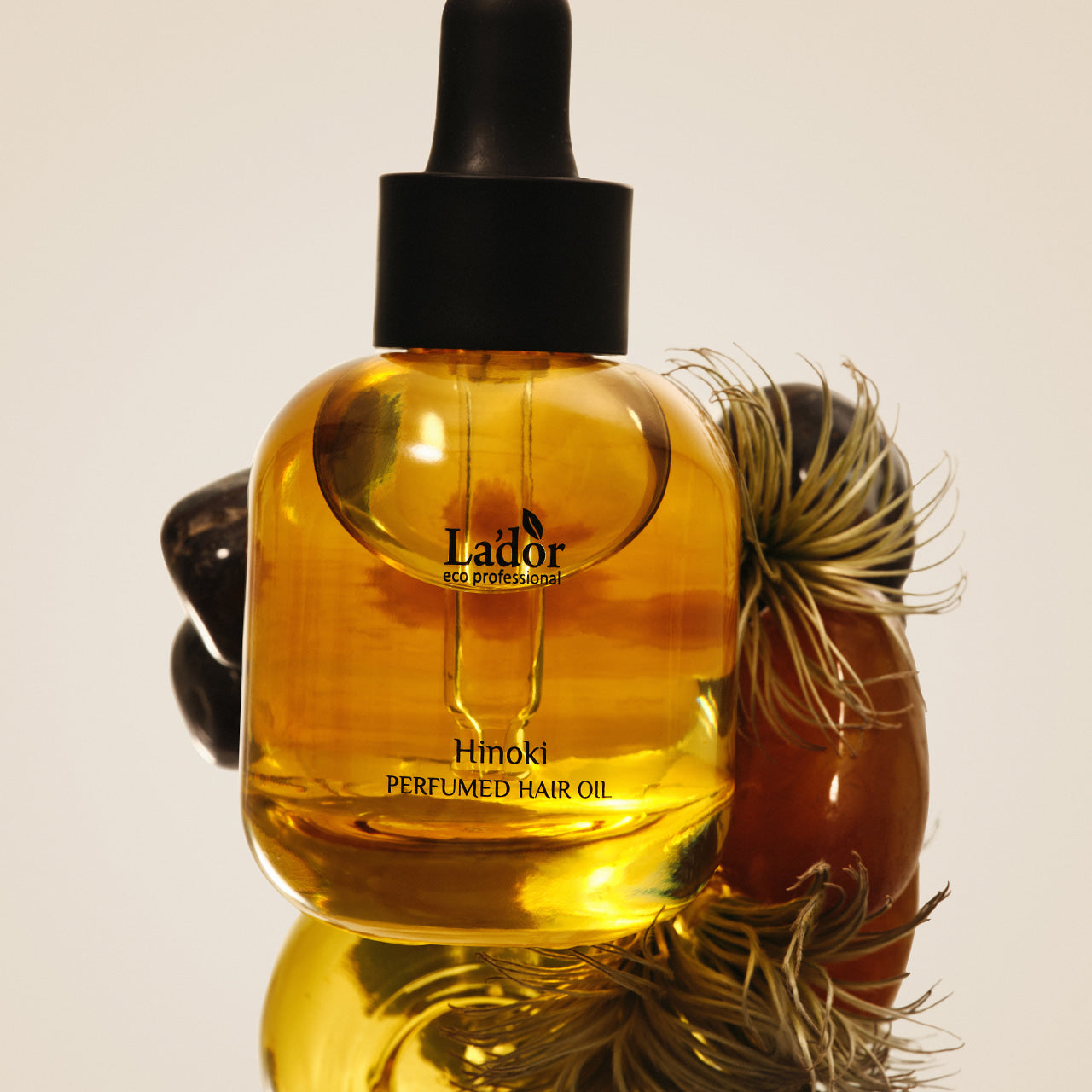 LADOR Perfume Hair Oil 30ml bottle on display with decorative elements, showcasing premium hair care product.