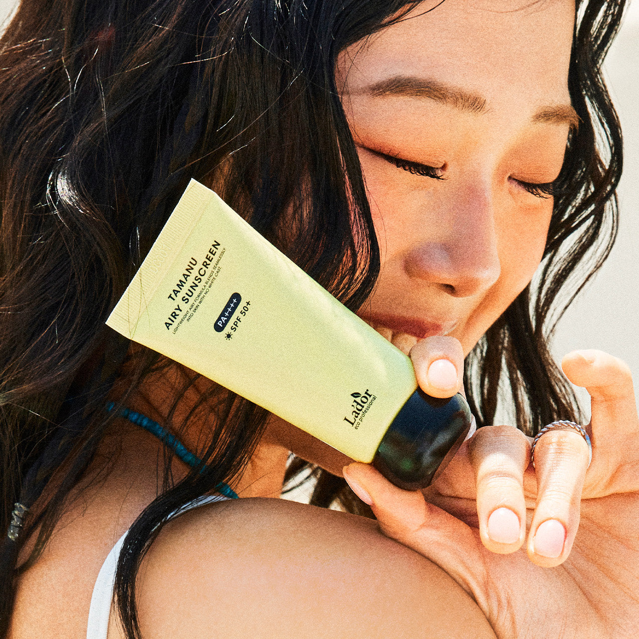Woman holding LADOR Tamanu Airy Sunscreen 50ml close-up