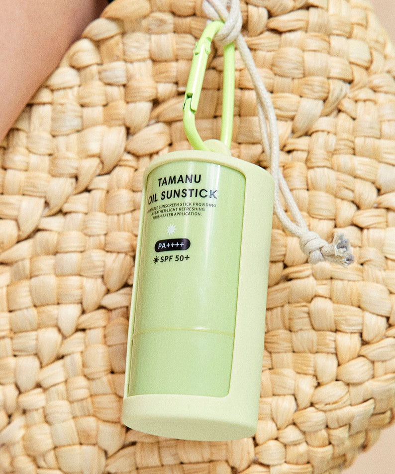 LADOR Tamanu Oil Sun Stick 21g hanging on a woven bag showing its portable design and SPF protection level.