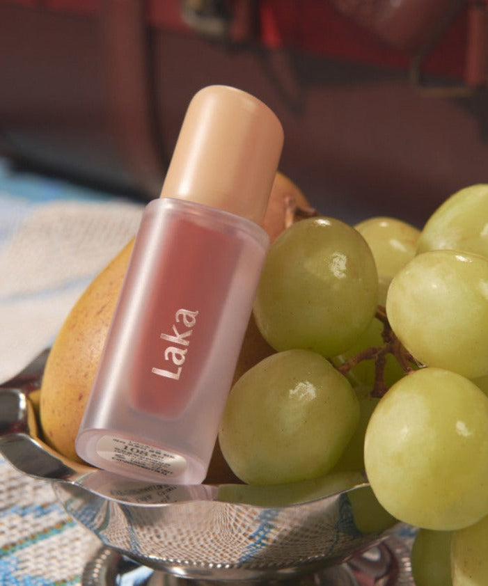 LAKA Fruity Glam Tint displayed elegantly beside fresh grapes.
