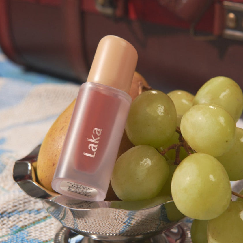 LAKA Fruity Glam Tint displayed elegantly beside fresh grapes.