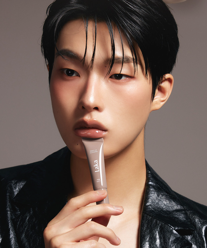 Person holding a tube of LAKA Fruity Lip Glossionner, showing glossy lip product in use.