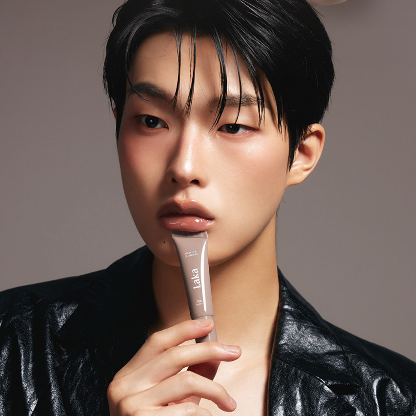 Person holding a tube of LAKA Fruity Lip Glossionner, showing glossy lip product in use.