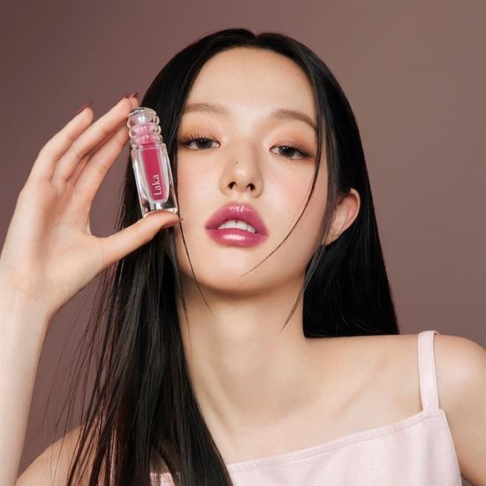 Person holding LAKA Maxi Glayer Tint, displaying its vibrant color on lips, beauty makeup product.
