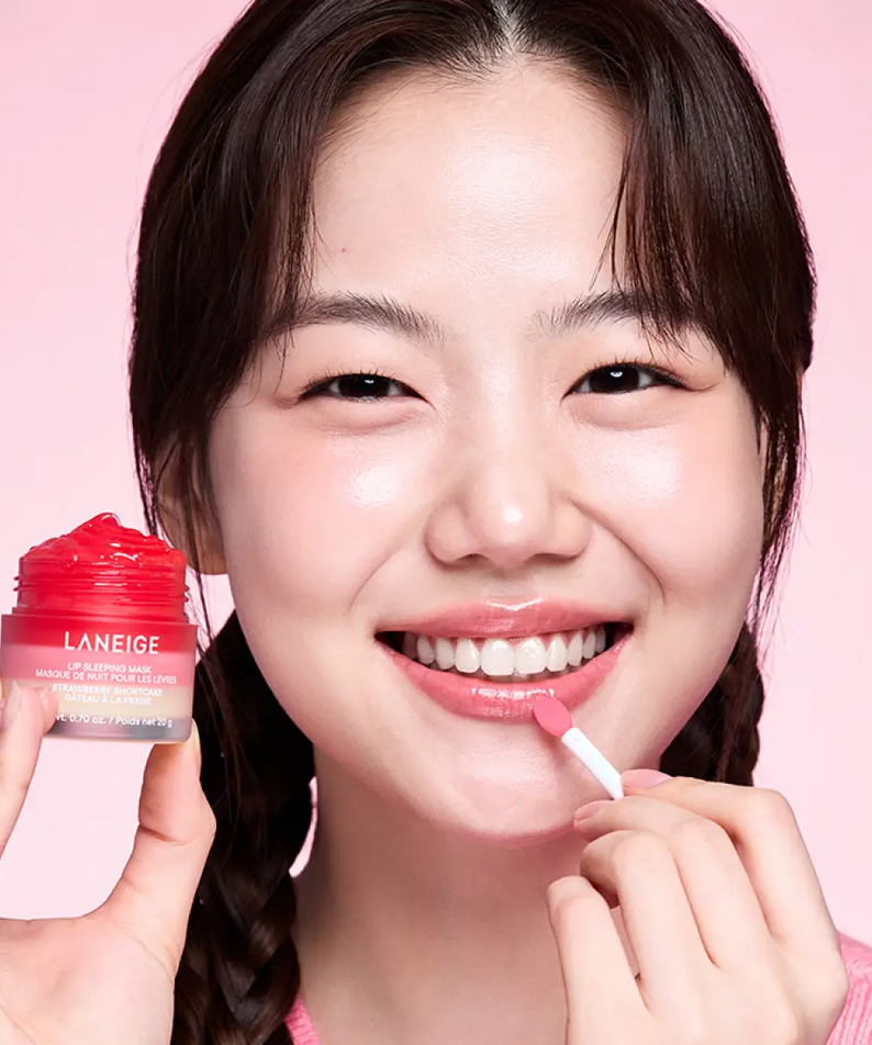 Woman applying LANEIGE Lip Sleeping Mask EX Strawberry Shortcake 20g with smiling expression and pink background.