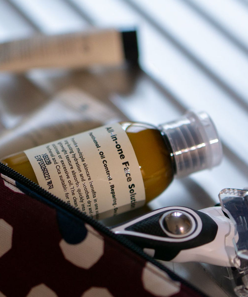 Gentleman Korea product shot featuring LAZY SOCIETY ALl-in-One Face Solution 50ml bottle in toiletry bag with razor