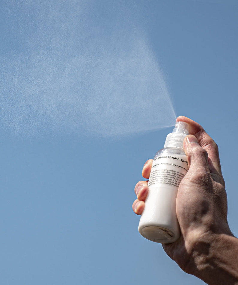 LAZY SOCIETY All-in-One Cream Spray 120ml being sprayed by a man’s hand against blue sky – Gentleman Korea Korean men’s skincare