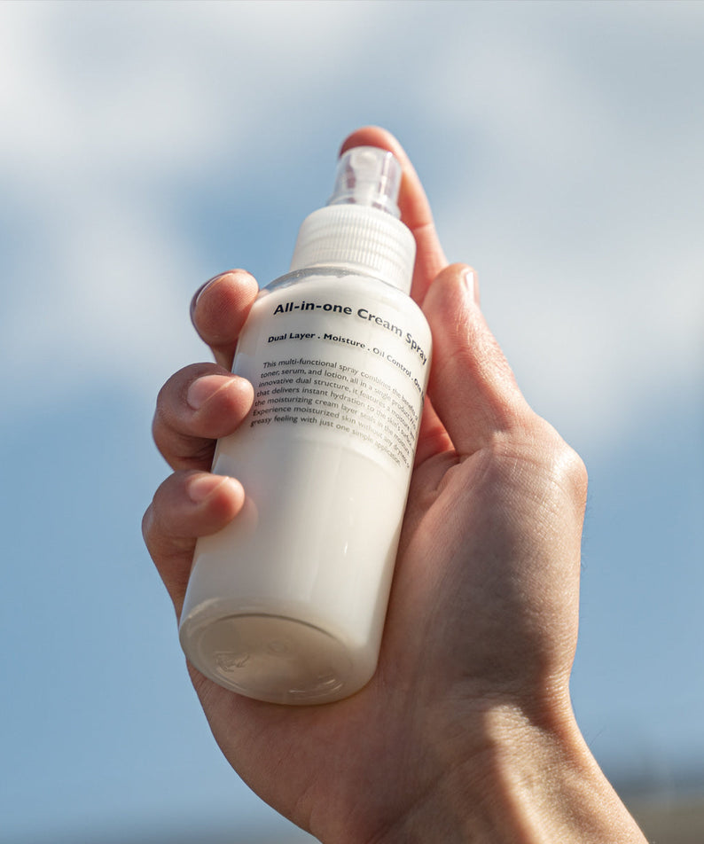 LAZY SOCIETY All-in-One Cream Spray 120ml held by hand against sky, Gentleman Korea men’s skincare product for gentlemen